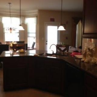 A cozy kitchen with a view of the dining area, featuring pendant lights and a central island.