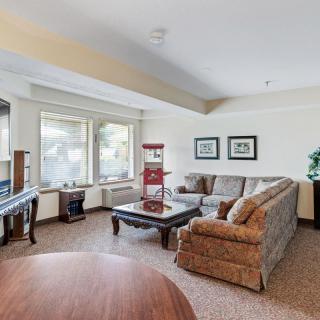A cozy living room featuring a sofa set and a coffee table, illuminated by natural light through large windows.