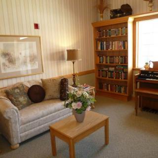 A cozy living room with a sofa, bookshelf, and a coffee table adorned with flowers.