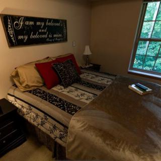 Cozy bedroom with a neatly made bed, decorative pillows, and soft lighting.