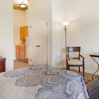 A cozy bedroom with a quilted bedspread, a lamp, and simple furniture.