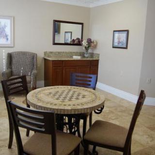 A cozy dining area with a round table and four chairs, complemented by a mirror and artwork on the walls.