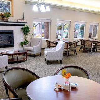 A cozy lounge area featuring comfortable seating, tables, and a fireplace.