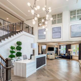 A modern lobby featuring a reception desk, staircase, and stylish decor.