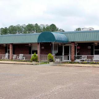 A welcoming commercial building with a green awning and seating area in front.