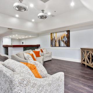 A modern living room with stylish decor, featuring a comfortable sofa, vibrant artwork, and sleek wood flooring.