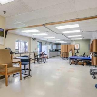 An empty rehabilitation center therapy room equipped with exercise machines and chairs.