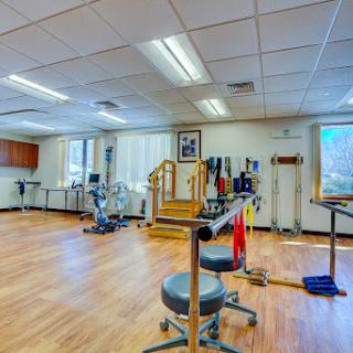 A well-equipped physical therapy room featuring various exercise equipment and a spacious layout for rehabilitation activities.