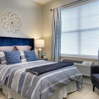 A modern bedroom with a stylish bed, matching pillows, and a lamp beside it.