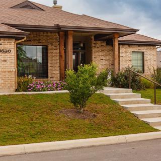 A suburban brick house with neatly landscaped front yard and stairs leading to the entrance.