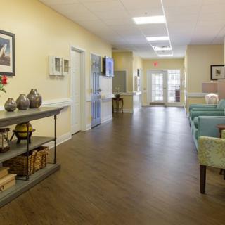 A well-lit hallway with wooden flooring, decorated with furniture and decorative items.