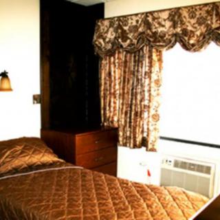 A cozy bedroom with a single bed, floral curtains, and an air conditioner.
