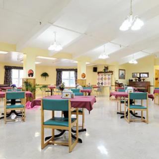 A spacious dining area with neatly arranged tables and chairs, decorated in warm colors.