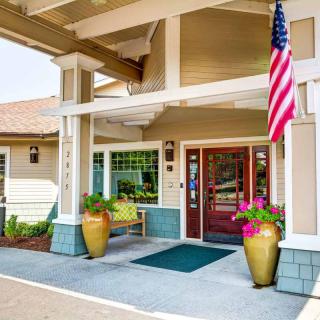 A welcoming building entrance featuring a doorway with potted plants and an American flag.