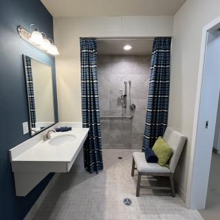 A modern bathroom with a walk-in shower, plaid curtains, and a minimalistic design.
