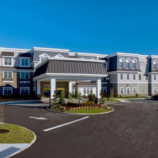 A modern residential building with a landscaped entrance and clear blue sky.