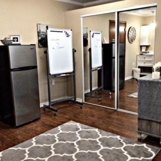 Office space with a whiteboard, refrigerator, and mirrored closet.