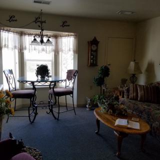 A cozy living room with a dining area by the window, featuring plants and comfortable seating.