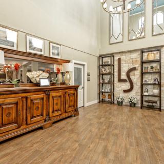 A welcoming entryway featuring elegant wooden furniture, decorative shelves, and a chandelier.