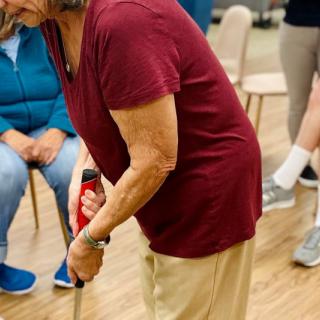 An elderly person participates in a group exercise or physical therapy session indoors.