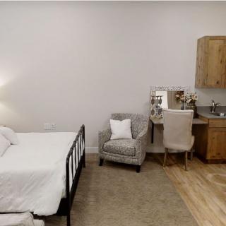 A cozy bedroom with minimalist decor featuring a bed, a chair, and a desk.