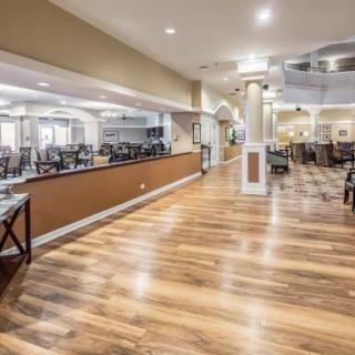 A spacious and modern restaurant interior with wooden floors and empty dining tables.