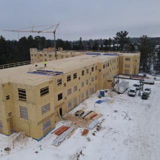 A winter construction site featuring a partially built wooden structure surrounded by snow.