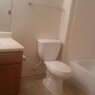 A simple bathroom with a toilet, sink, and bathtub.