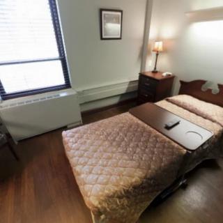 A small bedroom with a single bed, nightstand, and lamp.