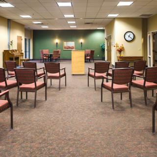 An empty conference room with arranged chairs and a podium at the front.
