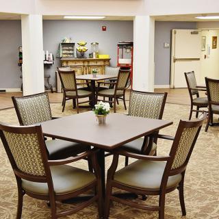 A cozy dining area with tables and chairs, featuring a small refreshment station in the background.