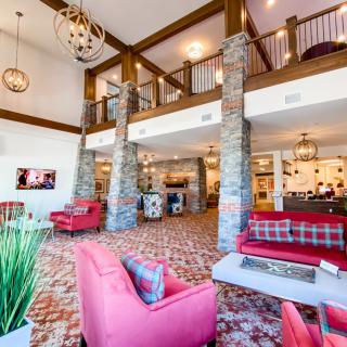 A modern and spacious hotel lobby with red sofas and stone columns.
