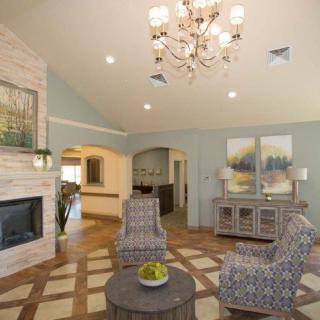 A modern living room featuring a chandelier, fireplace, and stylish furniture.