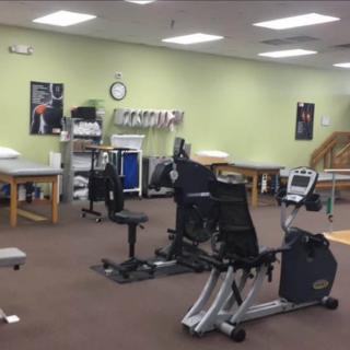 A rehabilitation center with exercise equipment and therapy tables.