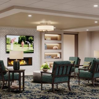 A modern living room featuring a cozy seating area with a television above the fireplace, complemented by elegant lighting and decor.