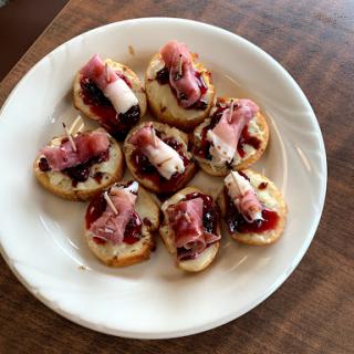 A delightful platter of bite-sized appetizers topped with prosciutto and a hint of sweetness.