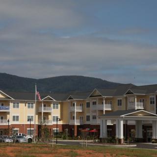 A residential building with mountains in the background under a partly cloudy sky.