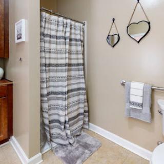 A cozy bathroom featuring a striped shower curtain, neatly organized towels, and decorative mirrors.