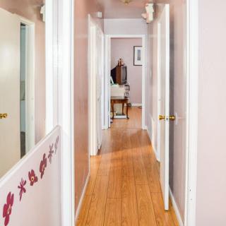 A view down a home hallway with wooden floors and multiple doors on either side.