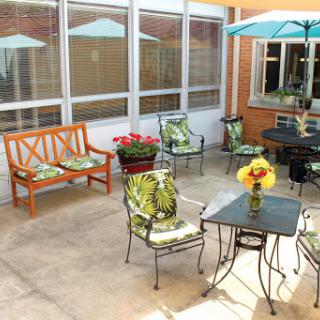 A cozy outdoor patio area with seating, a table, and vibrant flowers, perfect for relaxation.