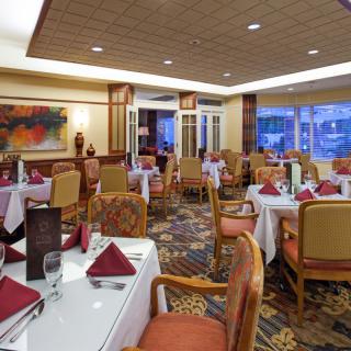 An elegant restaurant dining room with neatly arranged tables and chairs, decorated with stylish table settings.