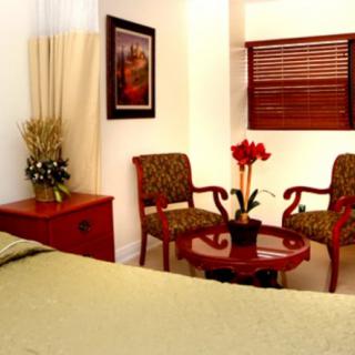 A cozy bedroom with two patterned chairs, a round wooden table, and decorative plants.