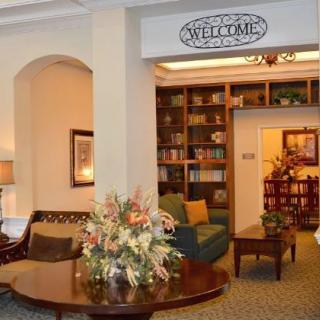 A welcoming lobby area featuring comfortable seating, decorative flowers, and a bookshelf.
