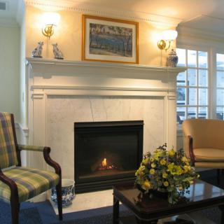 A cozy living room with a marble fireplace, elegant seating, and ambient lighting.
