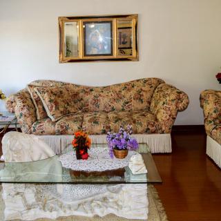 A cozy living room with floral-patterned sofas and a glass coffee table adorned with flowers.