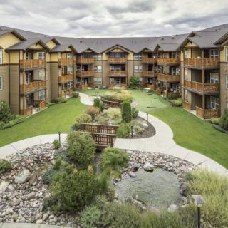 A scenic view of an apartment complex with a landscaped courtyard featuring lush gardens and winding pathways.