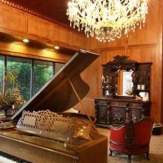A luxurious living room featuring a grand piano and an ornate chandelier.
