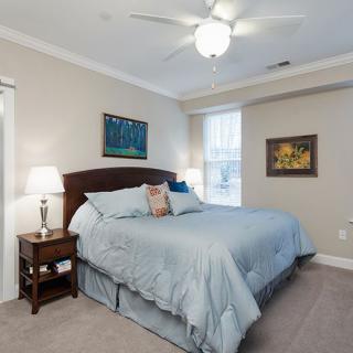 A cozy bedroom featuring a large bed with light blue bedding, flanked by nightstands with lamps, and decorated with wall art.