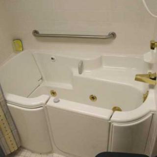 A walk-in bathtub designed for accessibility with a safety rail installed.
