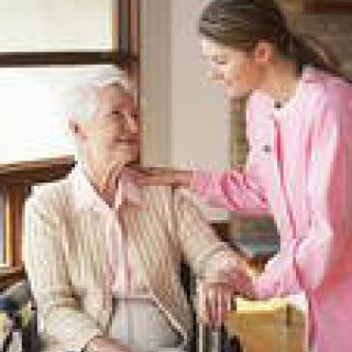 A caregiver assisting an elderly woman in a home setting.